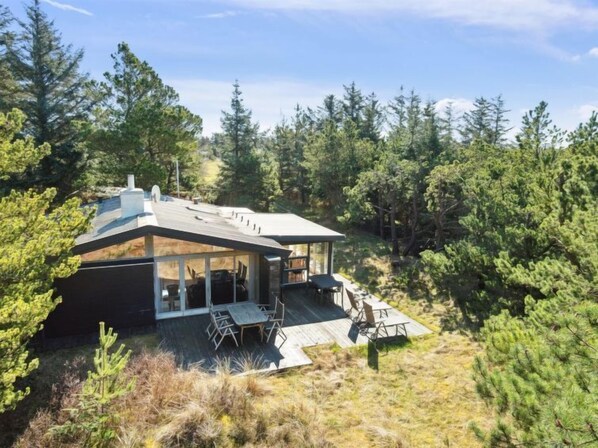 Enjoy panoramic views of the surrounding forest from the large glass front of this cabin, which features a spacious patio with outdoor seating.