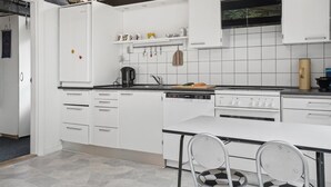 Ett modernt kök med vita skåp, en svart bänkskiva och en matplats med en rutig stol.