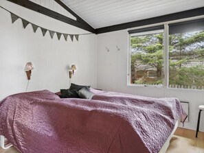 Relax in a serene bedroom with a large bed, natural views, and a cozy atmosphere.