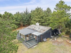 Enjoy a secluded stay in this house surrounded by a dense forest, with a clear view of the interior from the large front window.