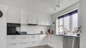 Cocina moderna con armarios blancos, lavavajillas Bosch y ventana con vistas a edificios.