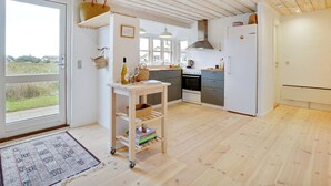A modern kitchen with wooden flooring, a built-in oven, and a white refrigerator.