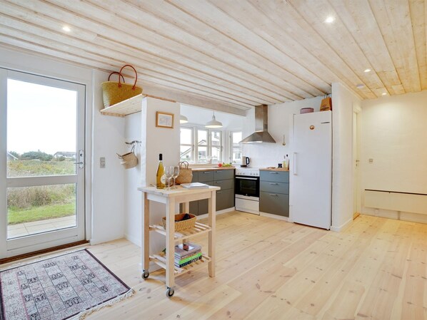 Een koelkast, een oven, een vaatwasser, kookgerei, borden en bestek