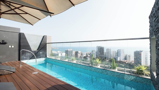 A rooftop pool with a city view, wooden deck, and a large umbrella. - 3BedRoom APT in the HEART of BARRANCO, LIMA, PERU 🇵🇪 (Barranco)