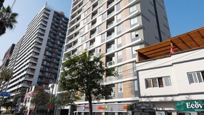 A tall residential building with multiple balconies, a surf shop, and a Biomart store. - 3BedRoom APT in the HEART of BARRANCO, LIMA, PERU 🇵🇪 (Barranco)