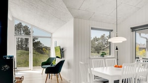 A modern dining area with white chairs, a white table, and a green chair. - "Raakel" - 950m from the sea by Interhome (Thisted)