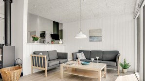 A modern living room with a grey sofa, a wooden coffee table, and a kitchen in the background. - "Raakel" - 950m from the sea by Interhome (Thisted)