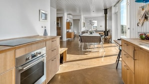 A spacious kitchen with wooden cabinets, a built-in oven, and a dining area with a table and chairs.