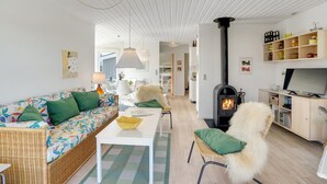 En hyggelig stue med sofa, stole, et bord, en pejs og et fjernsyn.