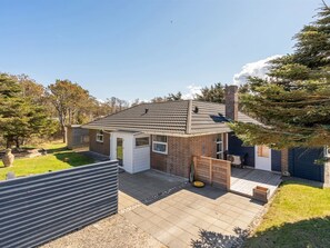 A single-story house with a tiled roof, a brick exterior, and a small deck.