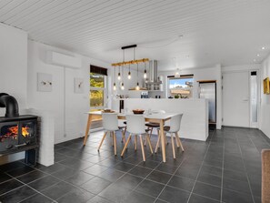 A modern kitchen with a central island, dining table, and chairs.
