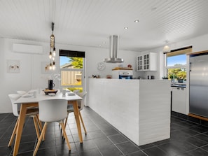 A modern kitchen with a central island, white cabinetry, and a dining area with a white table and chairs. - "Örjan" - 400m from the sea by Interhome (Thisted)