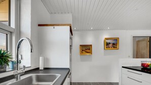 Een moderne keuken met een roestvrijstalen spoelbak, een zwart aanrechtblad en een wit kastje.