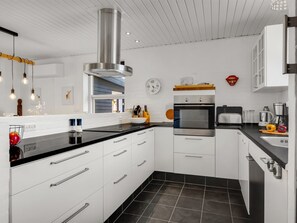 A modern kitchen with white cabinets, black countertops, and stainless steel appliances.