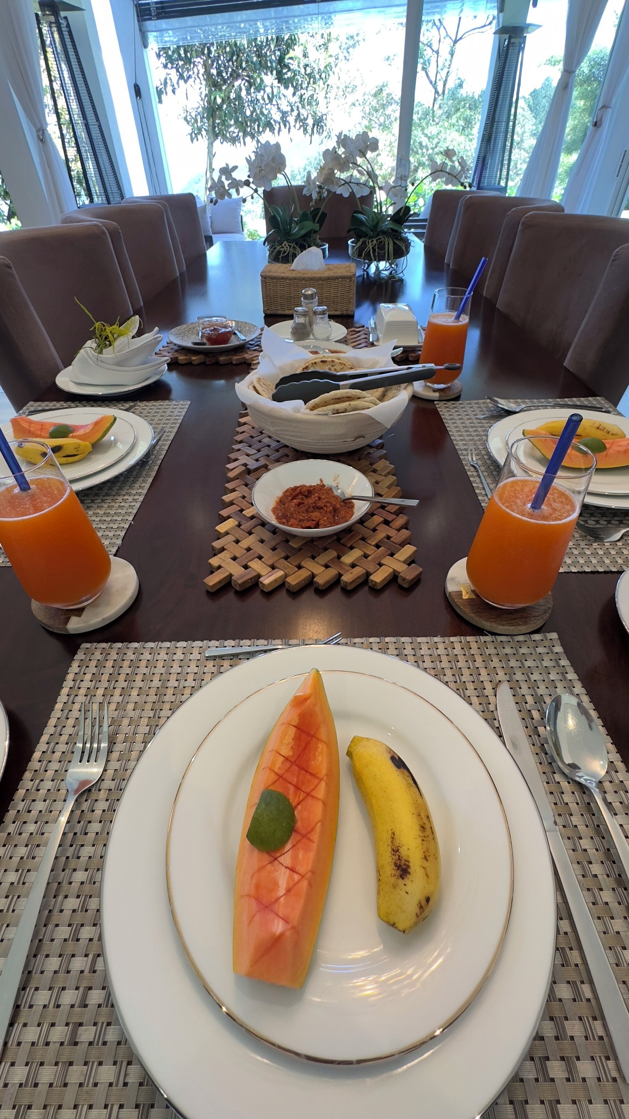 A dining table set with plates of food, including a carved vegetable and a banana, and glasses of orange juice.