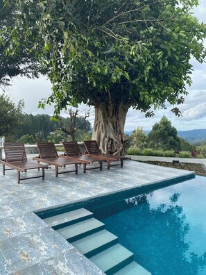 A pool area with lounge chairs and a large tree. - Benito Bungalow by The Serendipity Collection (Haputhale)