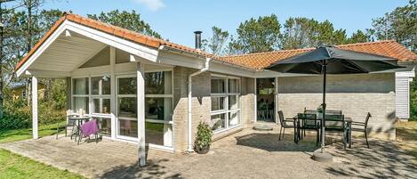 Een huis met een overdekte patio, een eettafel en zitplaatsen buiten.