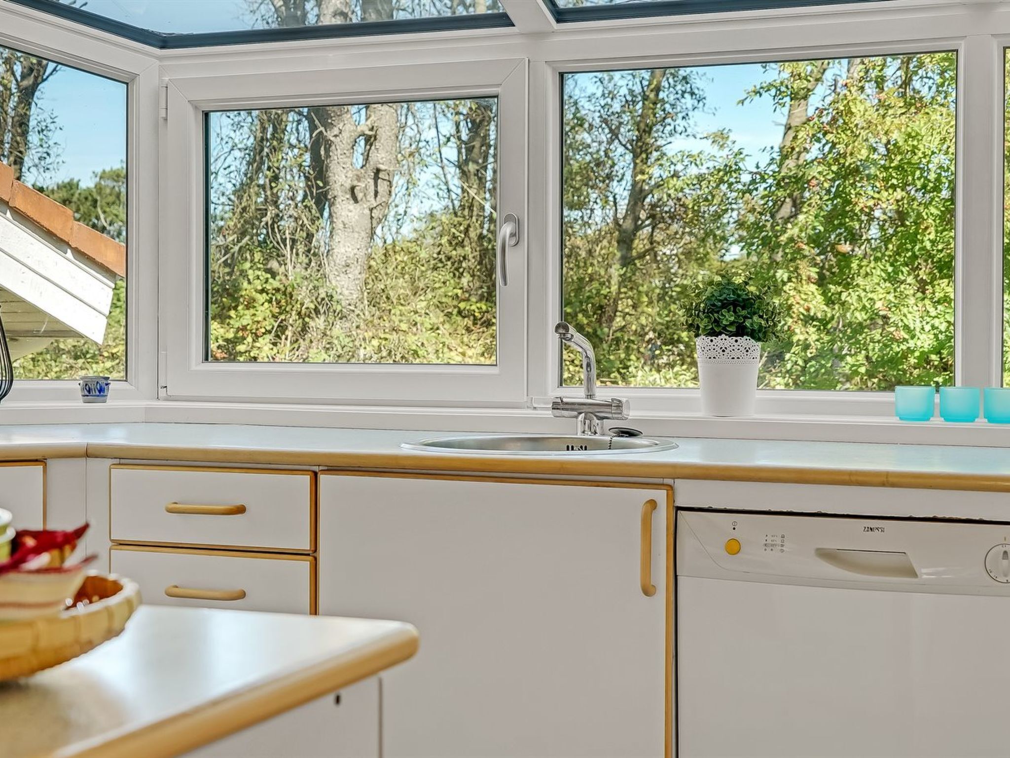 Een keuken met een groot raam, een spoelbak en een vaatwasser.