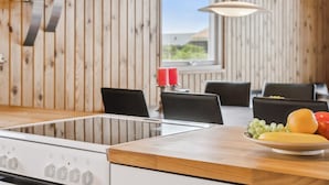 A kitchen with wooden paneling, a gas stove, and a dining area with a table and chairs.