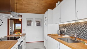 A modern kitchen with white cabinets, wooden countertops, and a tiled backsplash.