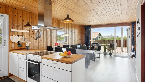 A modern kitchen with wooden paneling, a central island, and a dining area with a view.