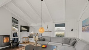 Un salon moderne avec une cheminée, un canapé, une table basse et un coin repas.