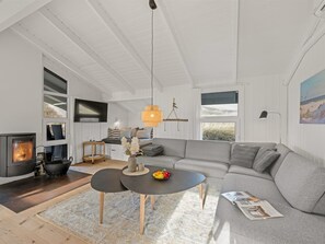 Un salon moderne avec une cheminée, un canapé, une table basse et un coin repas.