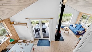 Een gezellig vakantiehuis met een eethoek, een woonkamer met een bank, en een groot raam met uitzicht op een terras.