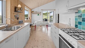 Een moderne keuken met een houten plafond, witte kasten en een groot fornuis.
