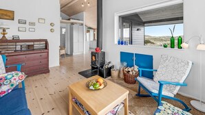 Een gezellige woonkamer met een open haard, houten meubels en uitzicht door een raam.