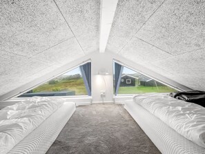 Een slaapkamer met twee bedden, een vloerbedekking en een uitzicht op een huis door een raam.