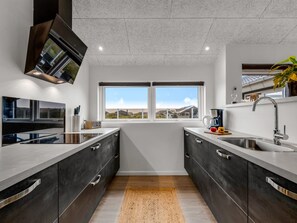 Een moderne keuken met donkere kastjes, een groot raam en uitzicht op het landschap.