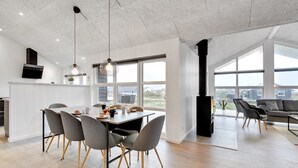 A modern kitchen with a dining area, large windows, and a fireplace.