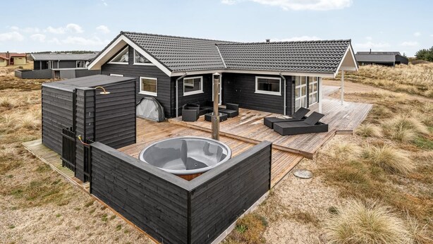 A modern beach house with a hot tub, outdoor seating, and a deck.
