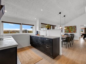 Une cuisine moderne dotée d’un îlot central, d’un coin repas avec des chaises et d’une vue sur l’extérieur.