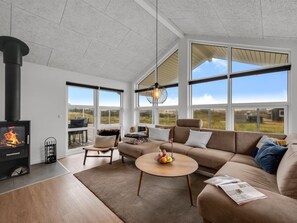 Un salon moderne doté d’une cheminée, de grandes fenêtres et offrant une vue sur l’extérieur.
