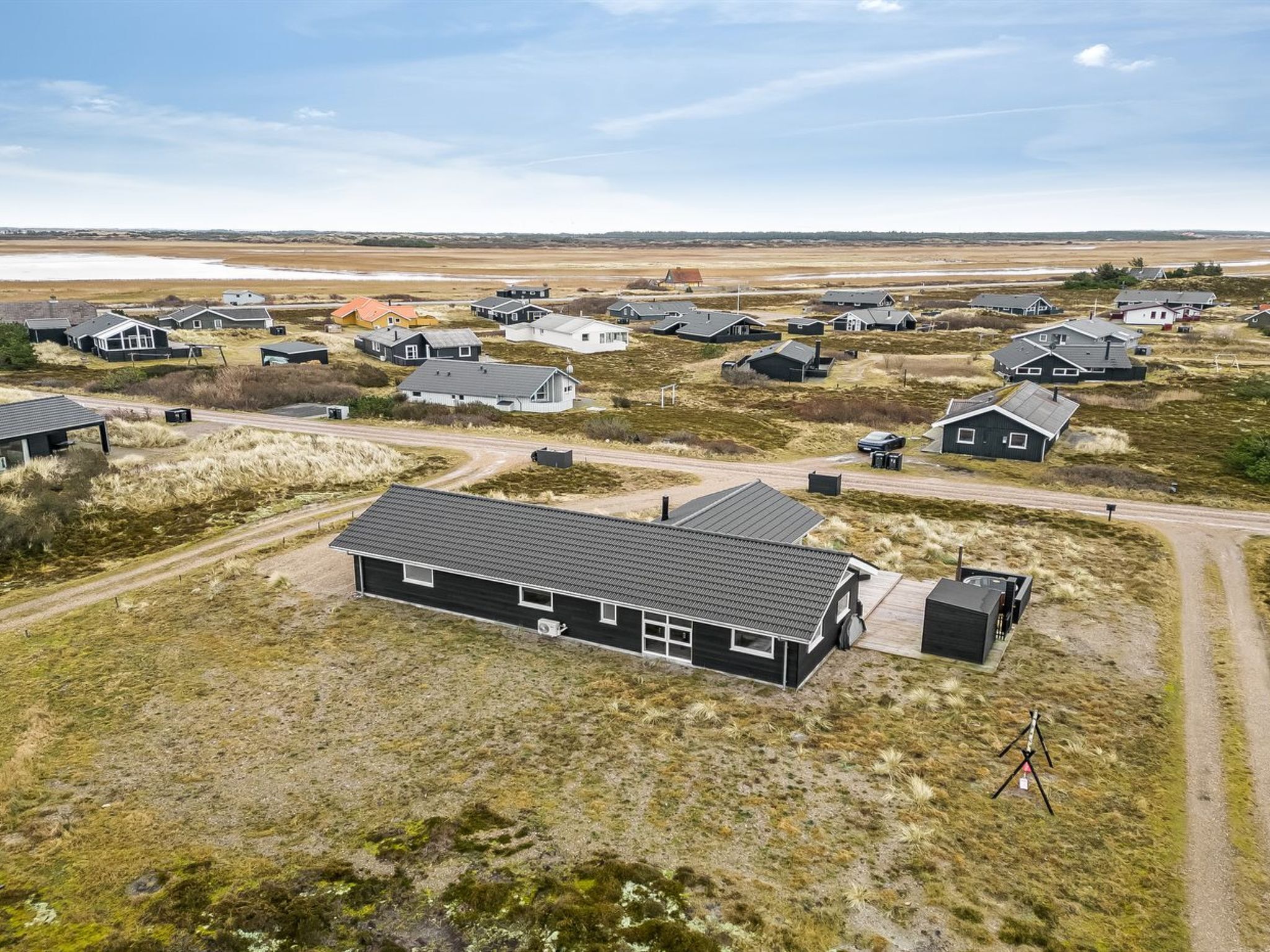 An aerial view of a residential area with houses, roads, and a body of water in the distance.