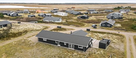 Vue aérienne d’un quartier résidentiel avec des maisons, des routes et une étendue d’eau au loin.