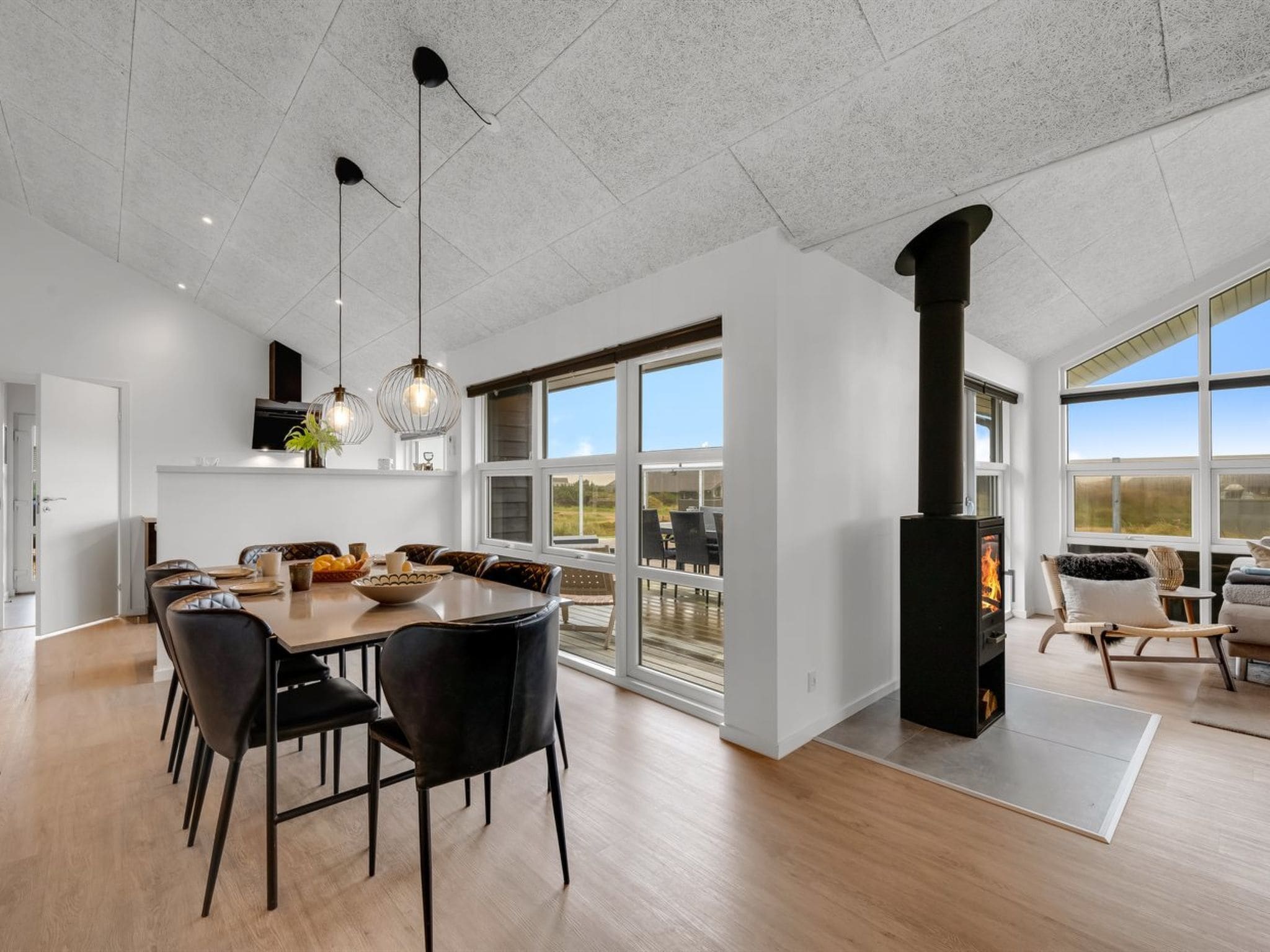 Un intérieur moderne comprenant un coin repas, une cheminée et de grandes fenêtres.