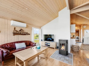 A living room with a leather sofa, a wooden coffee table, a television, and a fireplace.