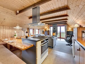 A spacious kitchen with a central island, wooden ceiling beams, and a large window providing natural light.