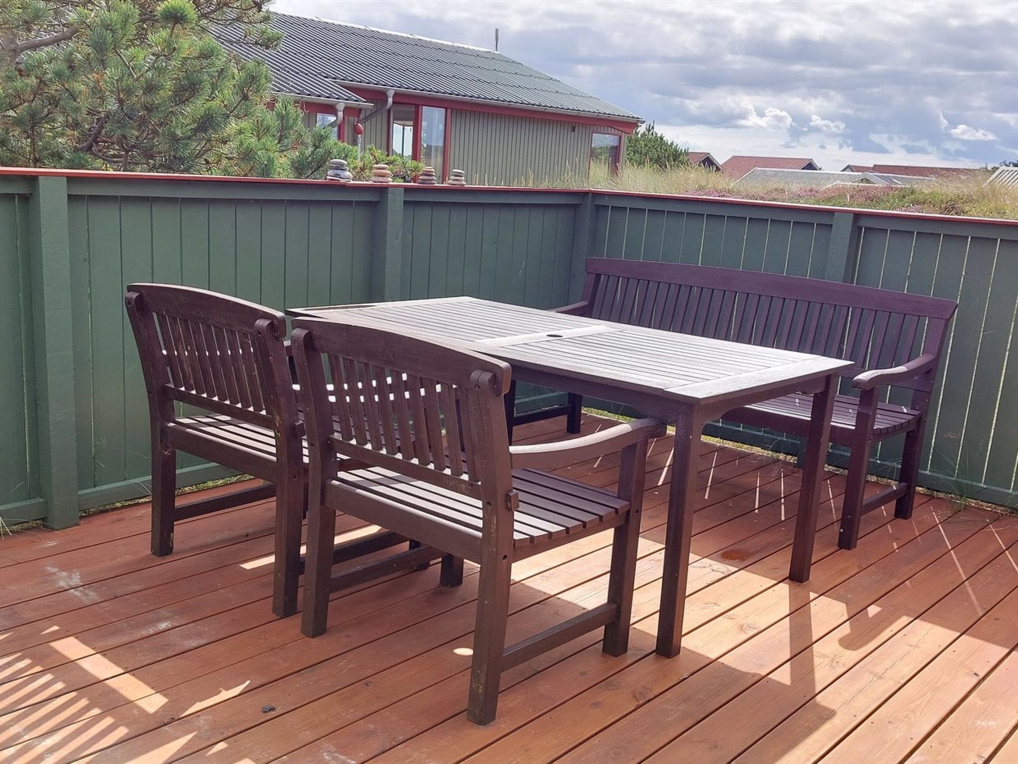 Eine Holzterrasse mit Tisch und zwei Bänken.