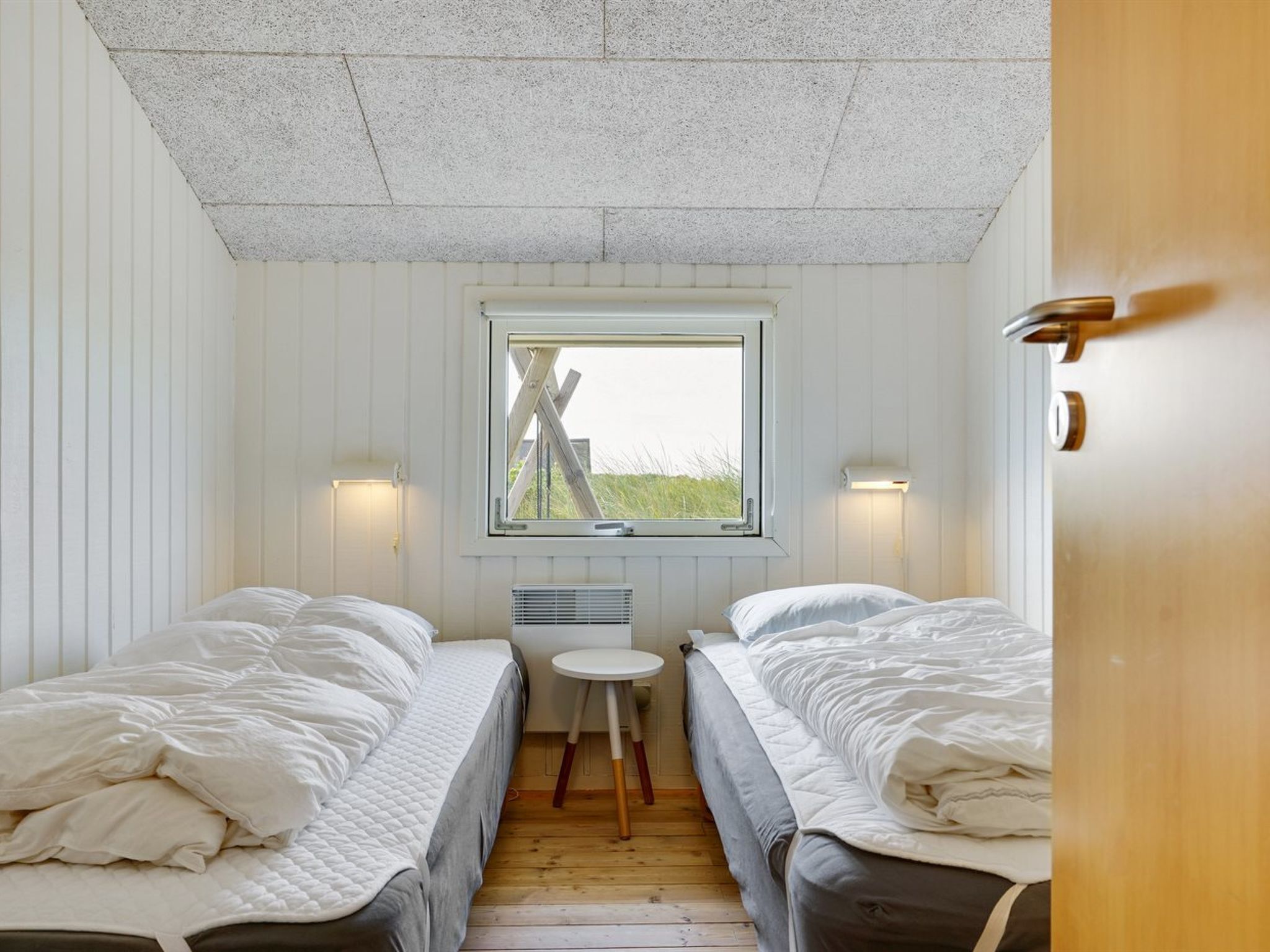 Una habitación pequeña y acogedora con dos camas, una ventana y una mesa.