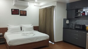 A hotel room with a bed, a kitchenette, and an air conditioning unit. - Palladium Luxury Suites  (Hyderabad)