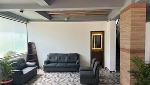 A modern lobby with a grey sofa, a matching armchair, and a patterned floor. - Palladium Luxury Suites  (Hyderabad)