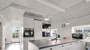 Una cocina moderna con muebles blancos, una isla central, horno empotrado y microondas.