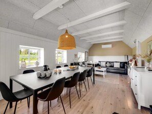 Un vaste espace dédié à la salle à manger, avec une longue table, des chaises et un luminaire suspendu.