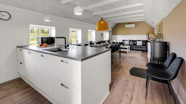 Una cocina amplia con una isla grande, un área de comedor con sofá y una sala de estar con chimenea.