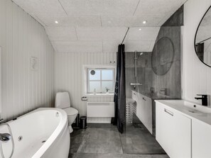 A modern bathroom with a bathtub, toilet, shower, and sink.