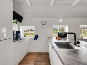 Une cuisine moderne dotée d’un grand îlot central, d’une machine à café et d’une horloge murale.